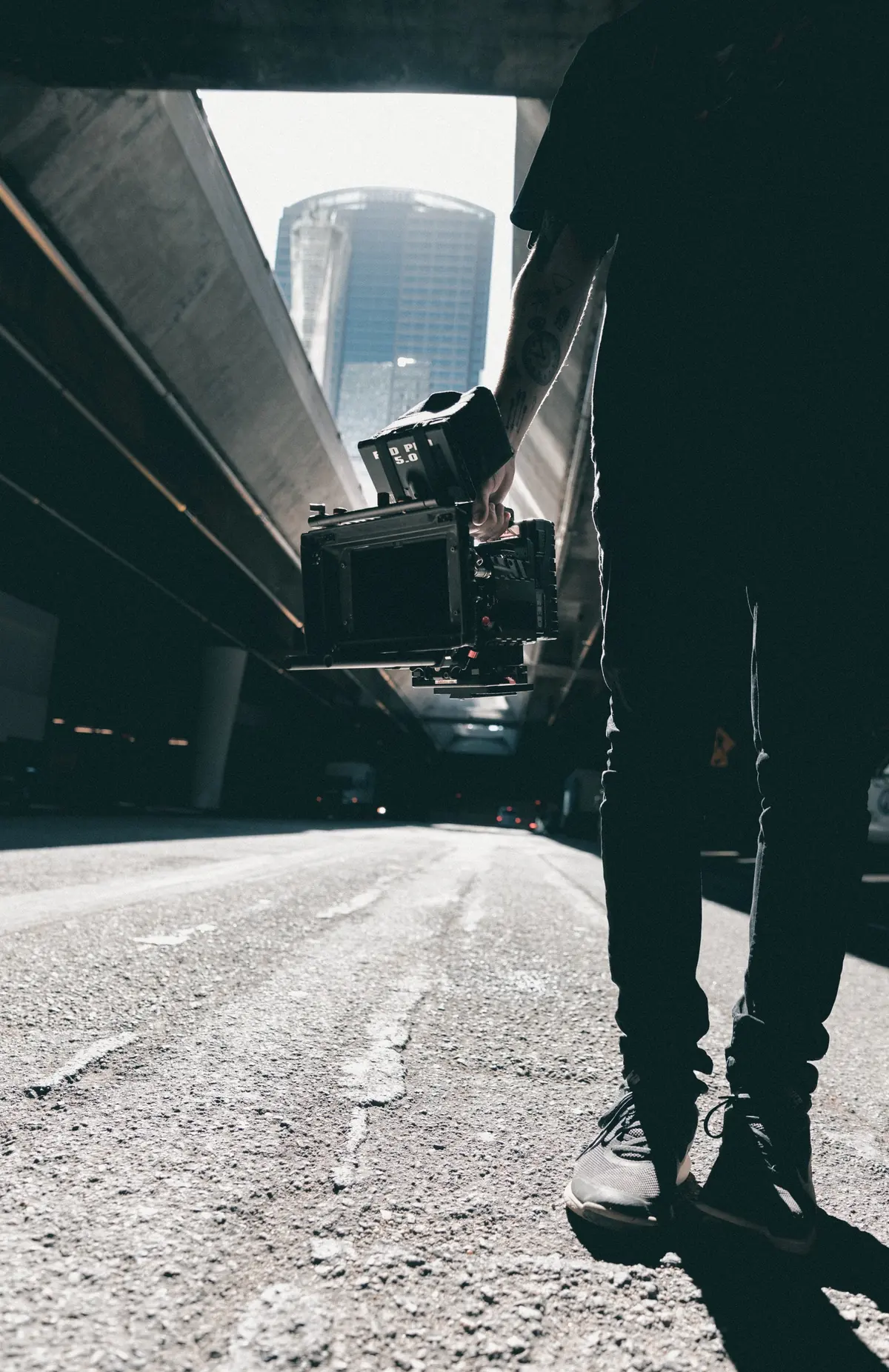 A person holding a video camera low on a city street